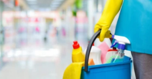 A professional cleaner in yellow gloves holding a caddy with cleaning supplies from Last Chance cleaning service in Dothan, AL.