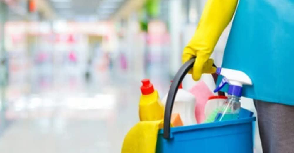 A professional cleaner in yellow gloves holding a caddy with cleaning supplies from Last Chance cleaning service in Dothan, AL.