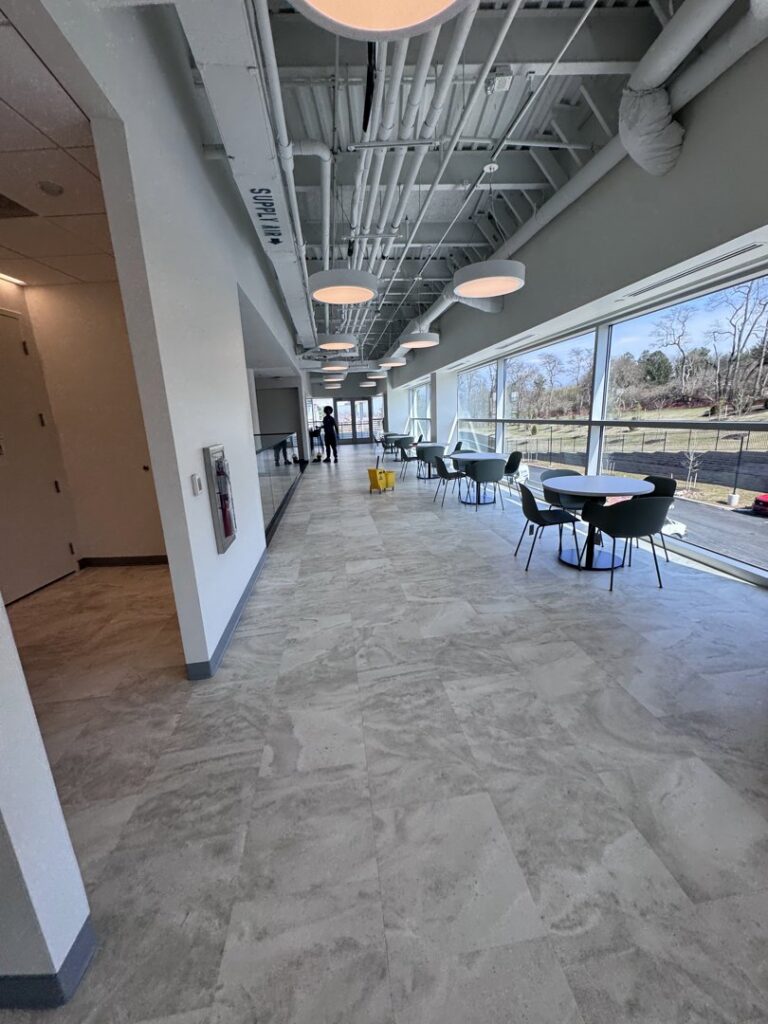 A cleaner pushing a yellow cleaning cart down a long hallway, demonstrating services by Statewide cleaning services llc in Philadelphia, PA.