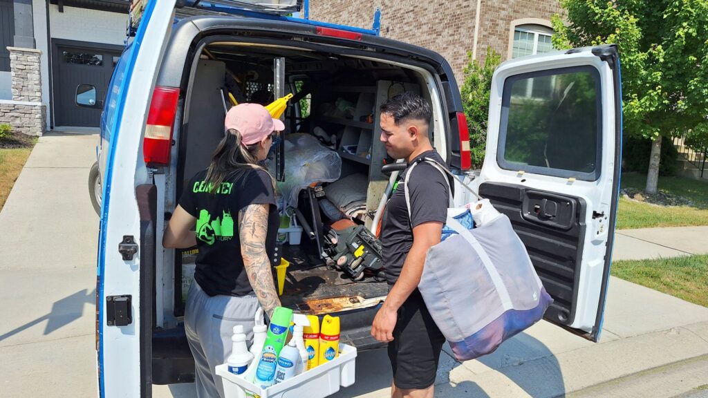 Two cleaners from Absolute Luxury, LLC Residential & Commercial Cleaning load cleaning supplies into a van in Antioch, TN.