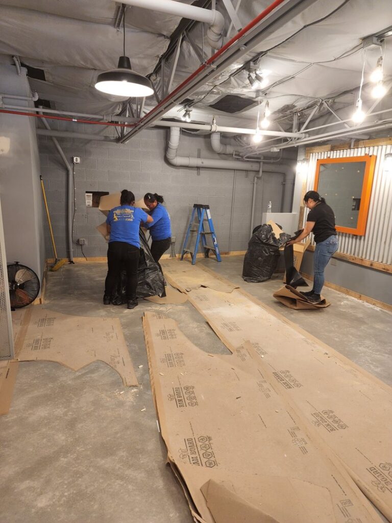 House cleaners performing post-construction cleanup, removing trash and cardboard for Arizona Housekeeping Service in Phoenix, AZ.