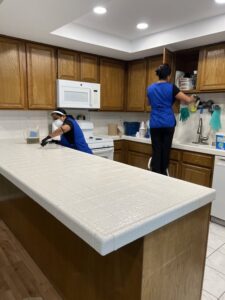 Two cleaners from Fabylous Cleaning Service scrubbing a kitchen counter and cleaning cabinets in Anaheim, CA.