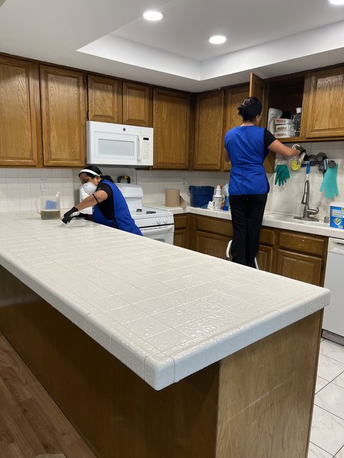 Two cleaners from Fabylous Cleaning Service scrubbing a kitchen counter and cleaning cabinets in Anaheim, CA.