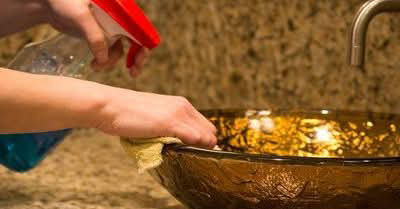 A person cleaning a bathroom sink with a spray bottle and cloth for ADW Cleaning LLC in Springfield, OR.