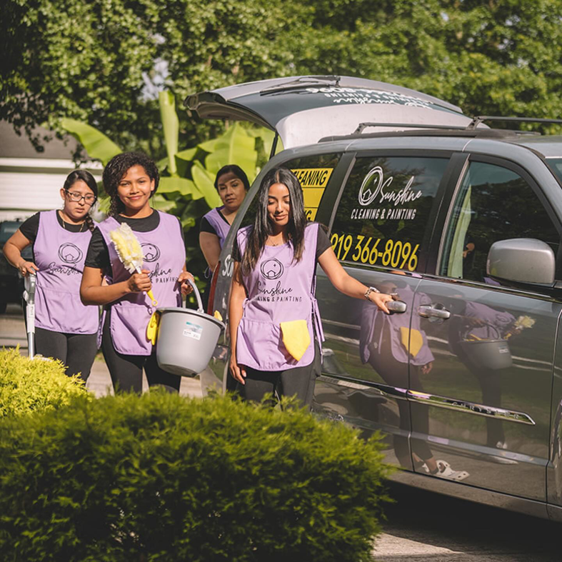 A cleaning crew arriving with supplies next to a branded company car for Sunshine Cleaning & Painting in Raleigh, NC.