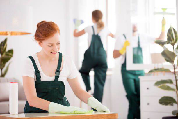 A professional cleaning crew in uniform wiping surfaces and cleaning windows in a home for Mike's Cleaning Crew in Cincinnati, OH