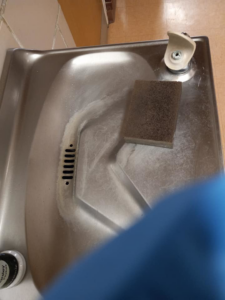 A scrubbing sponge on a dirty water fountain, showing cleaning in progress by J & A Cleaning and more in Norfolk, NE.
