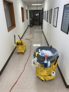 Professional cleaning equipment, including a mop bucket and supply caddy, set up in a hallway by Peoria Cleaning Pros, LLC in East Peoria, IL.