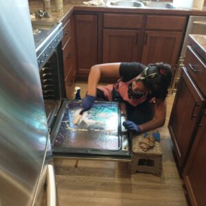 A professional cleaner from Leave The Dust To Me Cleaning Services LLC in Anchorage, AK, meticulously cleaning the interior of an oven.