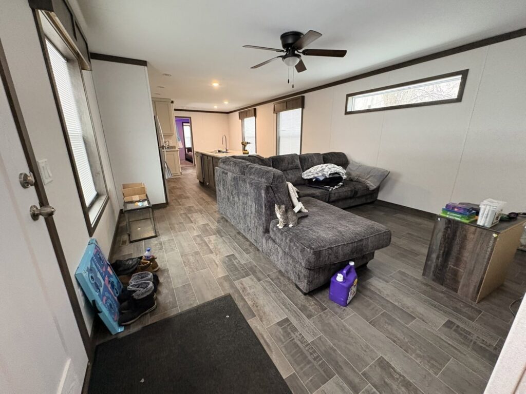 A purple cleaning product bottle on the floor in a living room, indicating cleaning work by Heavenly Harlots Maid Cleaning Services in Grand Forks, ND.