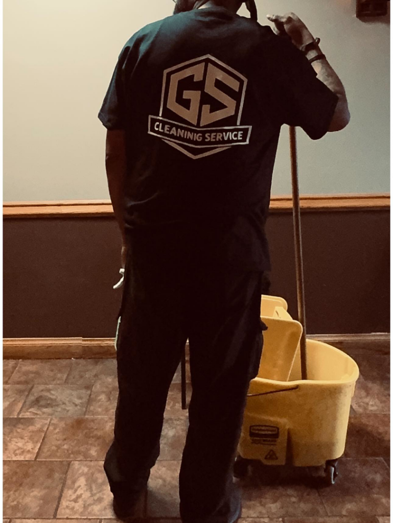 A cleaning professional holding a mop and standing by a bucket, ready to work for Genetic Solutions in Milwaukee, WI.