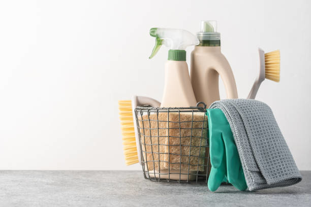 A basket filled with various cleaning supplies, including sprays, brushes, and gloves, from Clean Deeds in Olympia, WA.