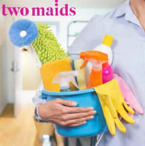 A person holding a blue bucket filled with various cleaning supplies for Two Maids of Hilton Head, SC.