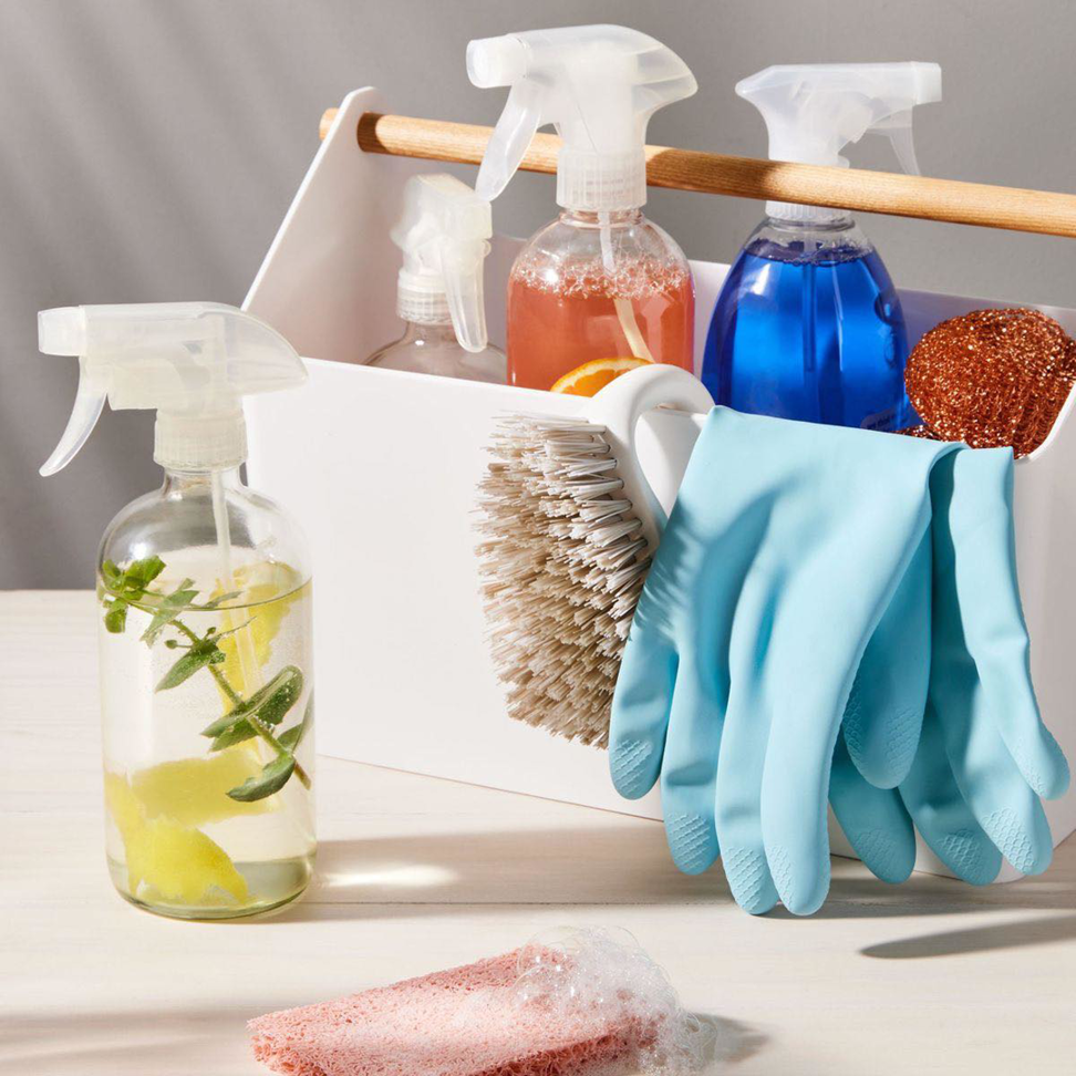 A caddy filled with various cleaning supplies, including spray bottles, gloves, and brushes, from Clean By Design, LLC in Norman, OK.