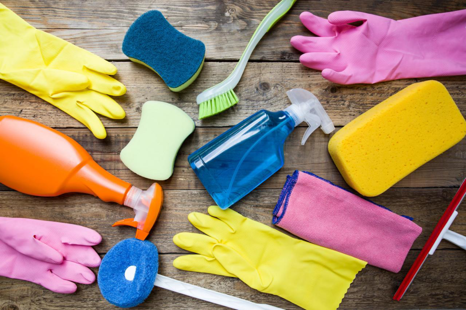 A flat lay of various colorful cleaning supplies including gloves, sponges, and spray bottles for KSG Cleaning Services in Fairmont, WV.