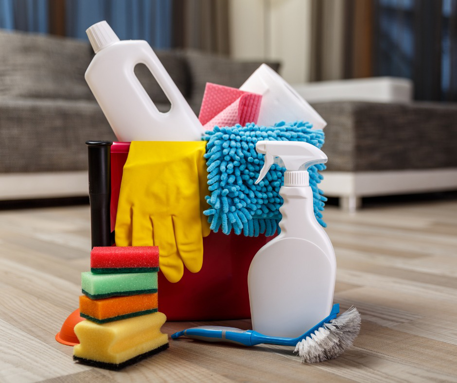 Various cleaning supplies including bottles, gloves, and sponges on a wooden floor, ready for house cleaning by Orange Cleaning Services in New Haven, CT
