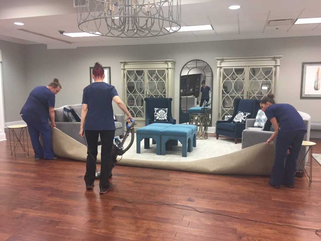 A cleaning team vacuuming a large rug in a living area, demonstrating thorough house cleaning by Precise Cleaning Solutions in Auburn, AL.