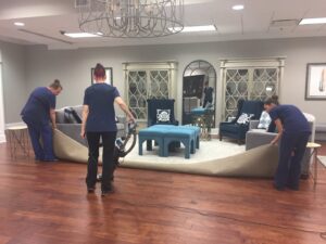 A cleaning team vacuuming a large rug in a living area, demonstrating thorough house cleaning by Precise Cleaning Solutions in Auburn, AL.