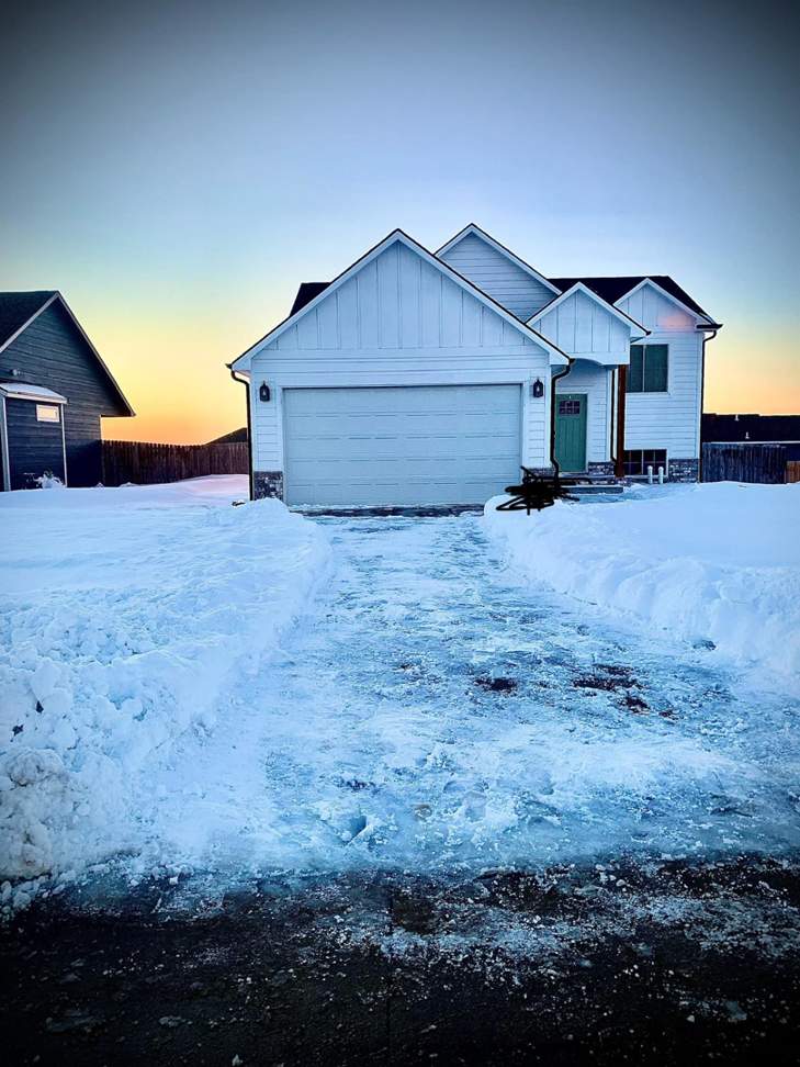 A residential driveway and front path cleared of snow and ice by Quinn's lawn care services in Colorado Springs, CO.