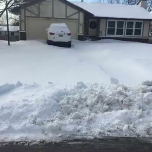 A residential driveway cleared of snow with a large snow bank, showcasing QUIKPLOW's snow removal service in Grand Rapids, MI.