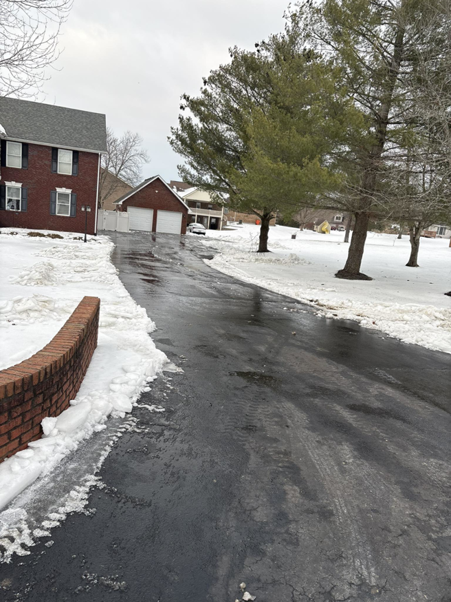 A residential driveway completely cleared of snow by Time 2 Grind in Ellenwood, GA, with snow piled neatly on the sides.