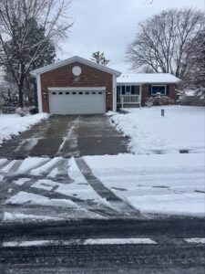A residential driveway partially cleared of snow by Snow Scholars - Snow Removal By College Students in Madison, WI.