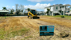 A cleared construction lot with a skid steer and a New Wave Concepts sign for demolition and site prep in Cape Coral, FL.