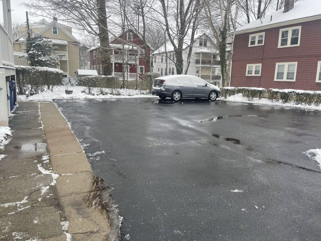 A parking lot cleared of snow with piles on the edges by Roger's Snow Removal and Landscaping Service in Boston, MA.