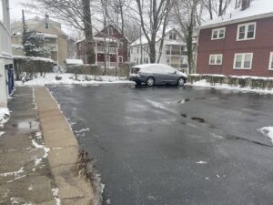 A parking lot cleared of snow with piles on the edges by Roger's Snow Removal and Landscaping Service in Boston, MA.