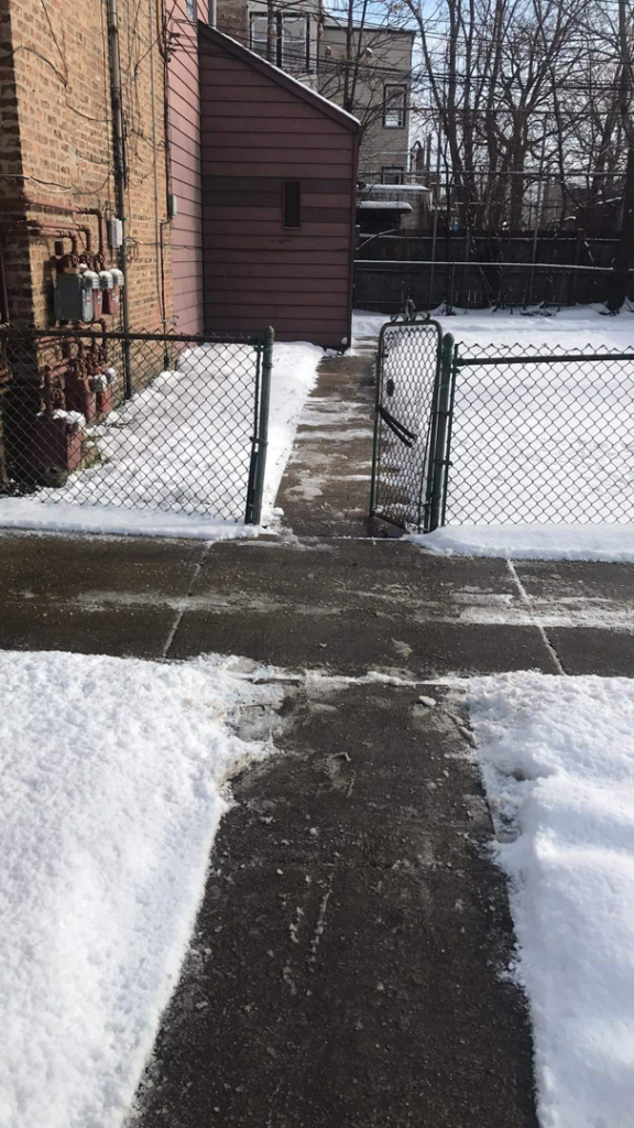 A cleared concrete path next to a building after snow removal by Apolonio's Snow Removal and Lawn care in Chicago, IL.