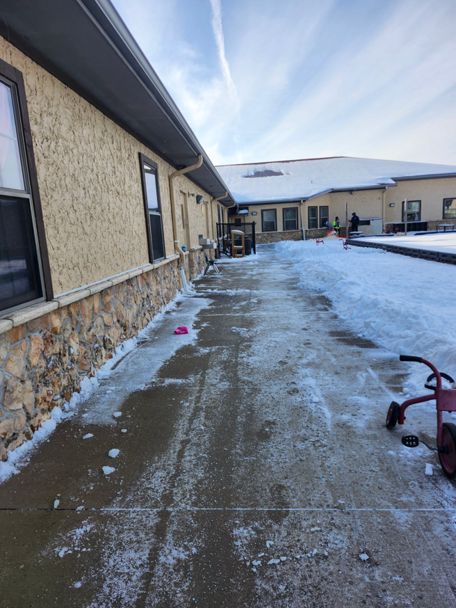A professionally cleared sidewalk with snow piled on the side by Bridgewood Landscape in Rogers, AR.