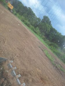 A cleared construction site with an excavator in the distance, managed by Cornerstone Demolition & Excavation in Lexington, KY