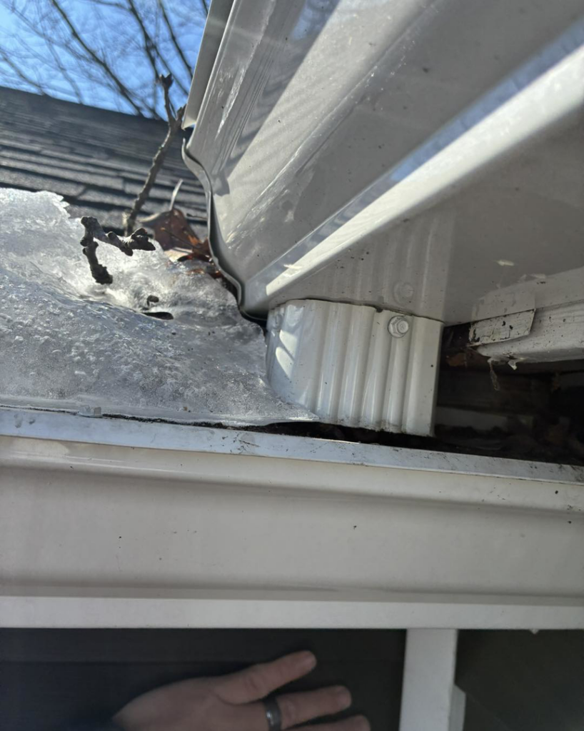A clogged gutter filled with ice and debris, posing a significant water damage risk, by Barbera Home Improvement in Parma, OH.