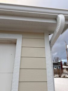 A close-up view of newly installed light beige siding, soffit, and gutter by Bishop Exteriors in Omaha, NE.