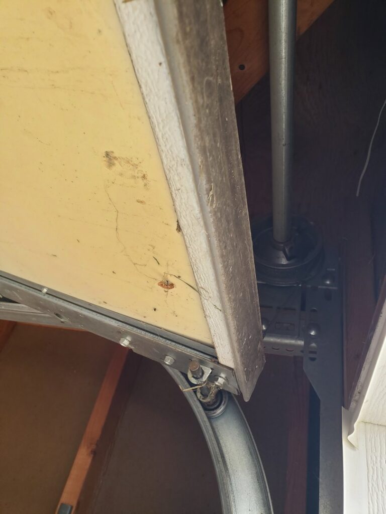 A close-up view of garage door tracks and rollers, demonstrating repair or installation work by PS GARAGE DOORS in Grand Forks, ND