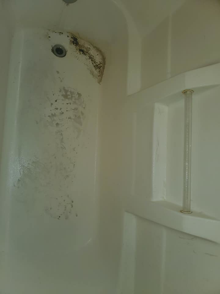 A close-up of a grimy bathtub with visible dirt and stains before cleaning by Tip Top Cleaning in Champaign, IL.