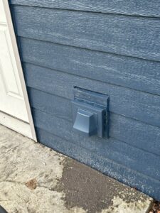 Close-up view of new dark blue siding with a matching dryer vent installed by Wisconsin Exteriors in Kaukauna, WI.