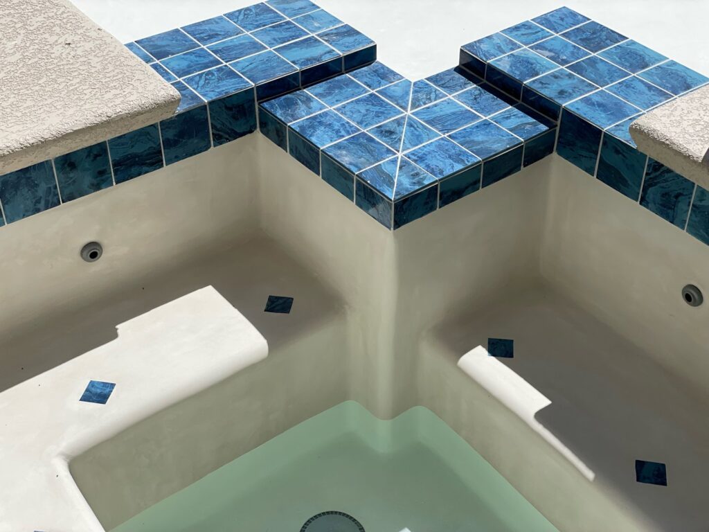 Close-up of a spa featuring blue mosaic tiles and a smooth white plaster finish by Fix A Pool in Las Vegas, NV