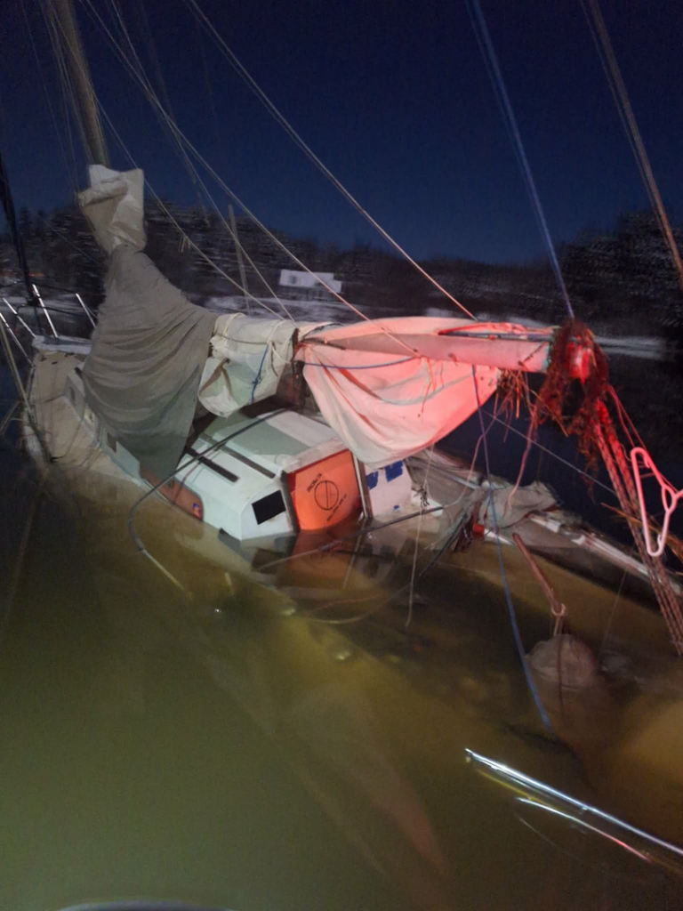 Close-up view of a partially submerged sailboat during a salvage operation by Downeast Marine Towing, LLC in Eastport, ME.