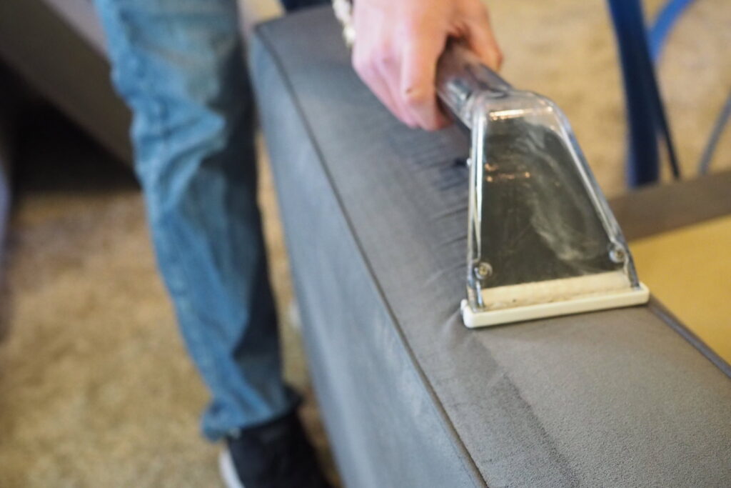 A close-up of a technician performing upholstery cleaning on a sofa by Idaho Gem Cleaning in Caldwell, ID.