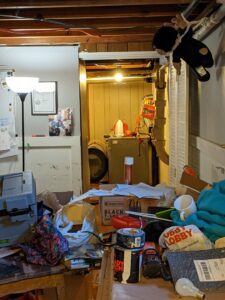 A cluttered basement with visible water damage on the floor and items, handled by North Shore Restore in Duluth, MN