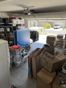 A cluttered garage filled with moving boxes and household items, typical of a moving day with Muscular Moving Men & Storage in Phoenix, AZ.
