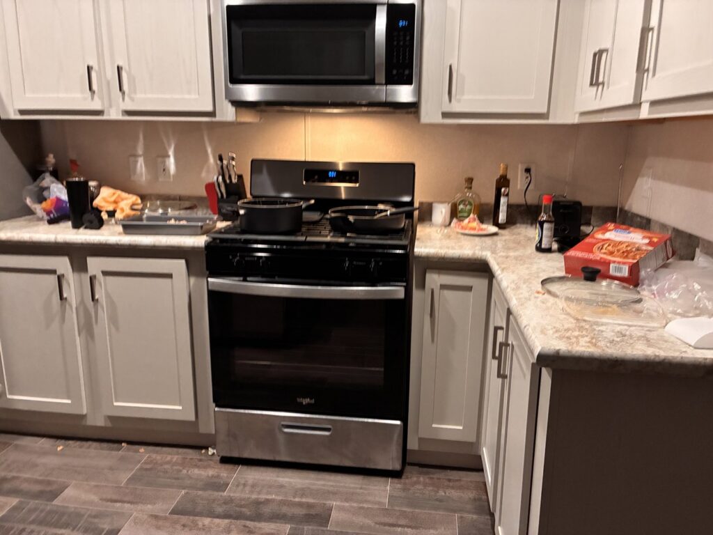 A cluttered kitchen with pots on the stove and items on the counter, a 'before' scene for Heavenly Harlots Maid Cleaning Services in Grand Forks, ND.