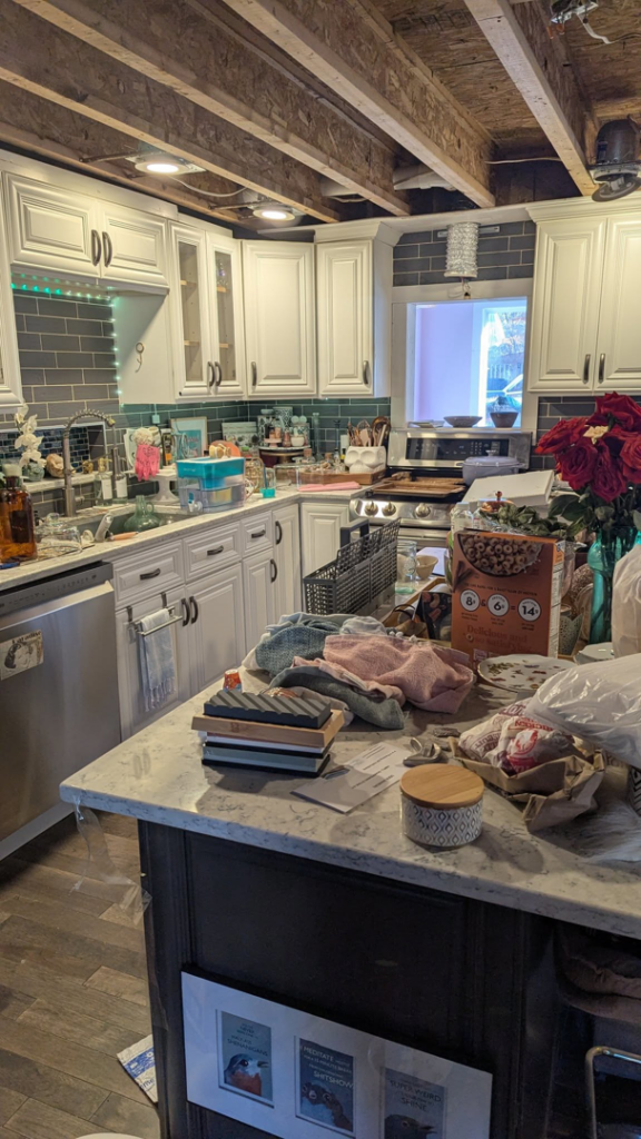 A cluttered kitchen countertop and island, representing a 'before' scene for house cleaning services by Larks Eco Clean in Bloomington, IN