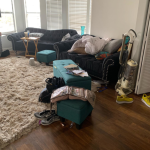 A cluttered living room with a vacuum cleaner, indicating a house cleaning service by Premier Uptown Clean in Charlotte, NC