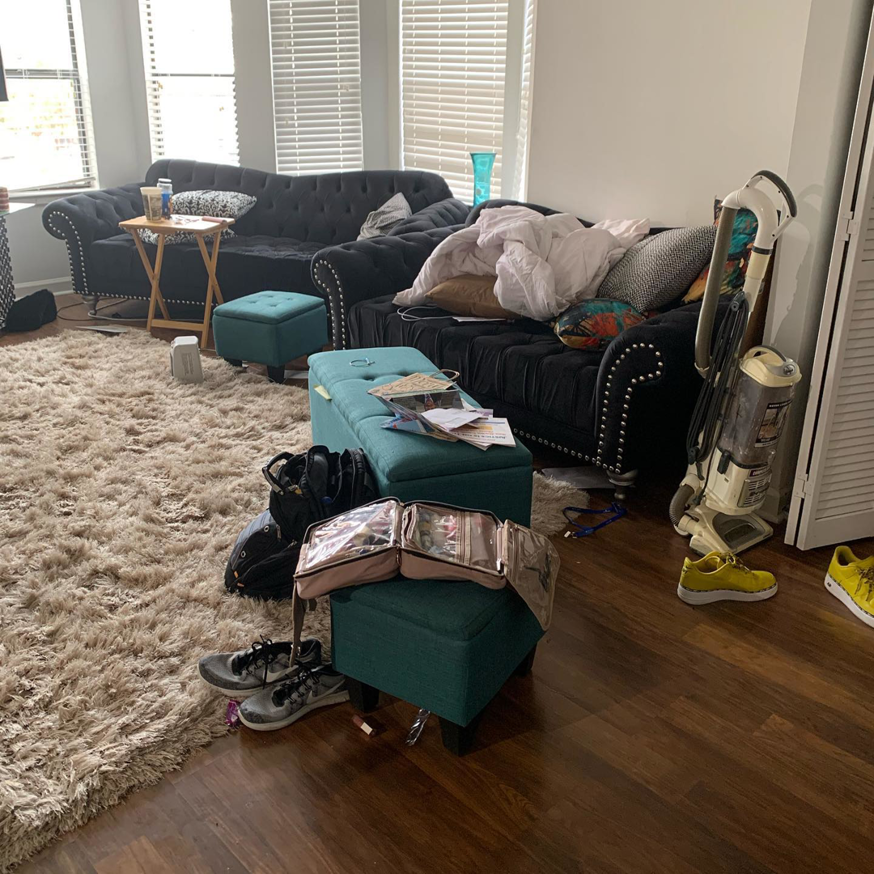 A cluttered living room with a vacuum cleaner, indicating a house cleaning service by Premier Uptown Clean in Charlotte, NC