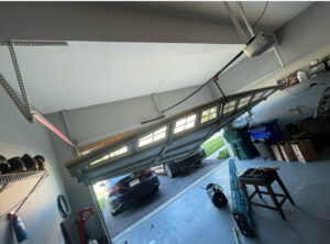 A severely collapsed and damaged garage door requiring urgent repair from Delaware Express Garage Door Service in Wilmington, DE