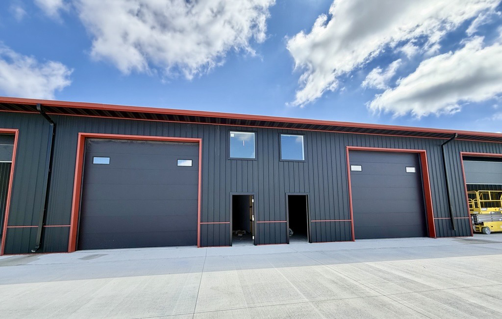 A commercial building featuring multiple dark panel garage doors, showcasing work by YETI Garage Door in Moorhead, MN.
