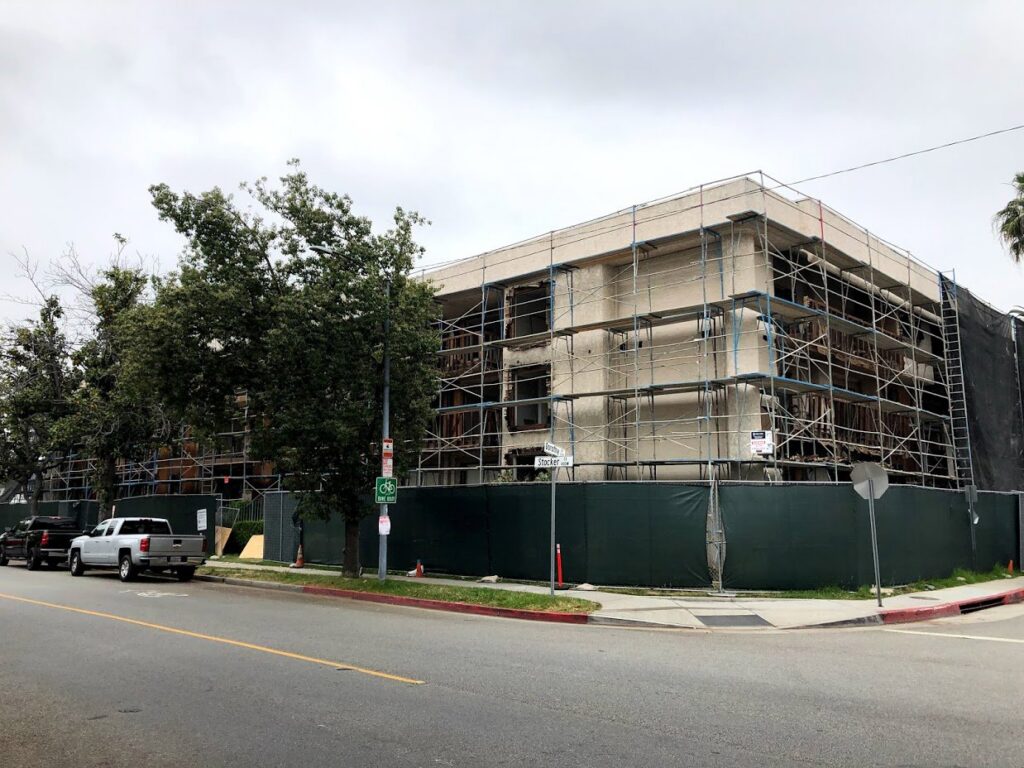 A commercial building undergoing demolition or major gutting, surrounded by scaffolding and safety fencing by DEMO Leaders in Los Angeles, CA
