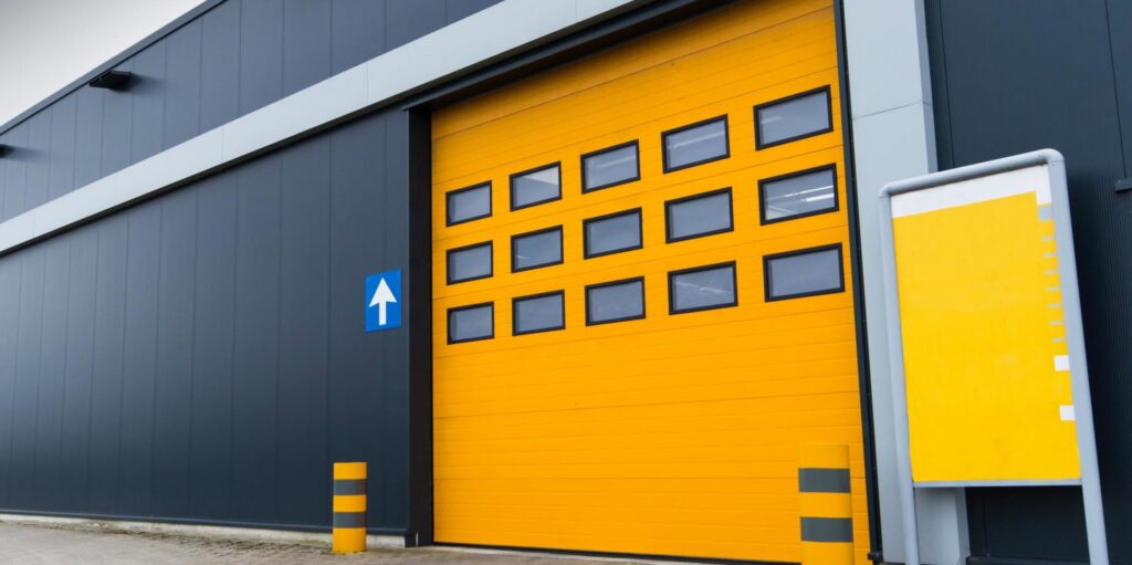 A commercial building featuring a large yellow garage door with multiple windows installed by Pioneer Overhead Door, Inc in Las Vegas, NV.